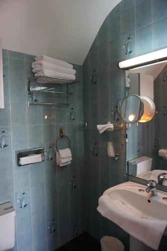 a bathroom with a sink and a mirror and towels at Hotel Ker Vennaik in Bénodet