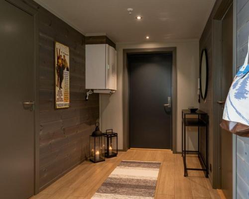 un pasillo con una puerta negra, una alfombra y un suelo en Riddertunet apartment 101, en Beitostølen