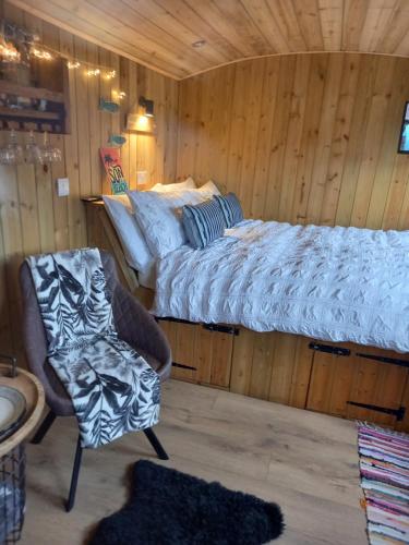 a bedroom with a bed and a chair in a room at Stargazy Shepherds Hut in St Ives
