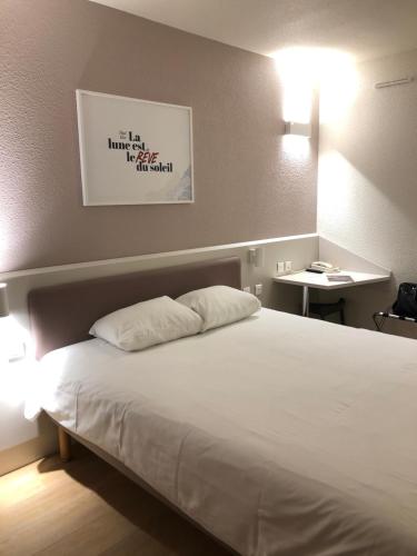 a bedroom with a bed with two pillows on it at ACE Hôtel Travel Fabrègues - A9 Montpellier Sud in Fabrègues