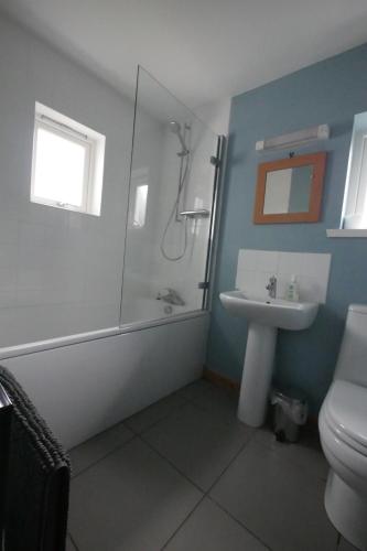 a bathroom with a shower and a toilet and a sink at Macleod Cottage - Isle of Lewis Self-Catering in Port of Ness