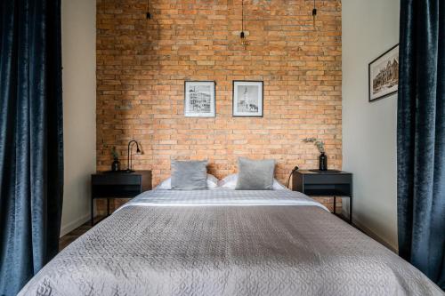 a bedroom with a large bed and a brick wall at CUTE Siauliai in Šiauliai