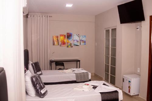 a hotel room with two beds and a television at Premier Hotel in Votuporanga