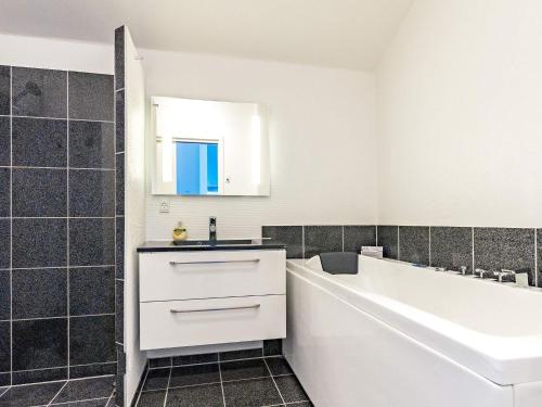 een witte badkamer met een wastafel en een bad bij 4 person holiday home in Bogense in Bogense