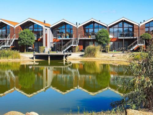 ボーゲンセにある4 person holiday home in Bogenseの池を前に建つ建物