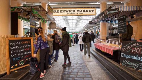 a group of people walking inside of a market at Elegant & spacious parkside 2-bedroom 2-bathroom flat in period building facing Blackheath - parking, great Greenwich location, easy for O2 Arena and City, very near Marathon start line! in London