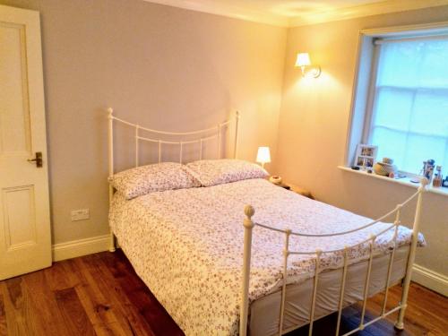 um quarto com uma cama com uma moldura branca e uma janela em Elegant & spacious parkside 2-bedroom 2-bathroom flat in period building opposite Blackheath Common - private entrance, great Greenwich location! em Londres