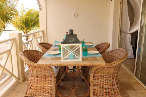 a dining room table with wicker chairs and a lamp at Caribbean Lofts Bonaire in Kralendijk