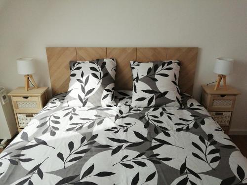 uma cama com lençóis e almofadas preto e branco em Duplex du Bois d'Amour em Quimper