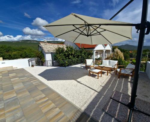 eine Terrasse mit einem Tisch und einem Sonnenschirm in der Unterkunft House Camellia with fenced pool and playground in Blizna Donja