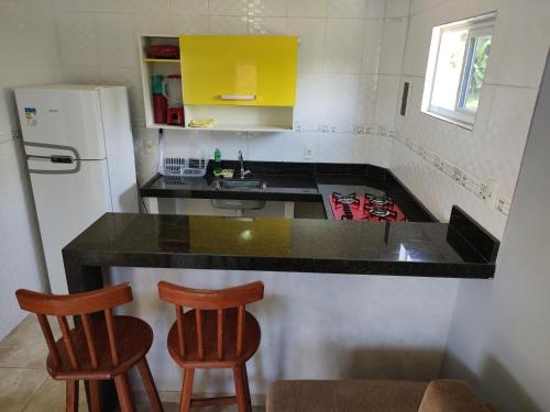 uma cozinha com um balcão preto e dois bancos de madeira em Apart. japaratinga em Japaratinga