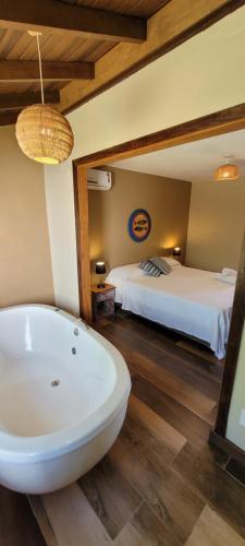 a bathroom with a bath tub and a bed at Pousada Capitão Cook in Praia do Rosa