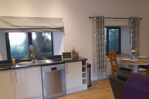 a kitchen with a sink and a table in a room at Thornmoor Barn in Lifton