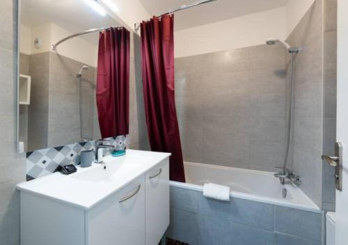 uma casa de banho com uma cortina de chuveiro vermelha, um lavatório e uma banheira em Cannes bel appartement familial avec piscine em Cannes