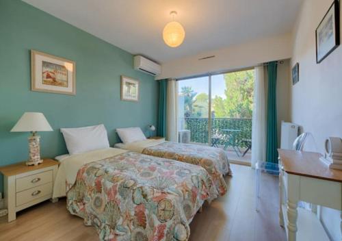 um quarto com 2 camas, uma secretária e uma varanda em Cannes bel appartement familial avec piscine em Cannes