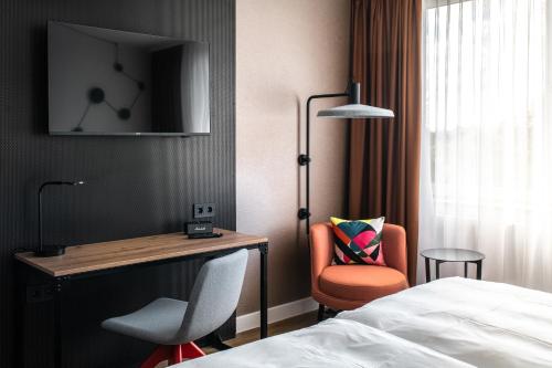 a hotel room with a bed and a desk and a chair at Pentahotel Bremen in Bremen