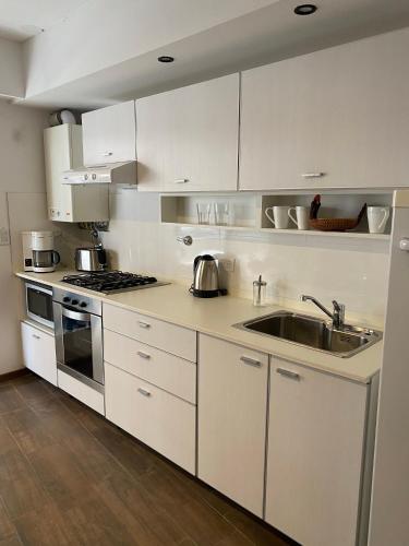 uma cozinha com armários brancos e um lavatório em Estudio completo en zona centro, a 200 metros del rio em Rosário