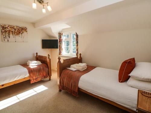 a bedroom with two beds and a window at Orchard Cottage in Ashbourne