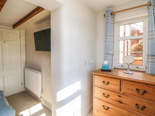a bedroom with a wooden dresser and a window at Orchard Cottage in Ashbourne