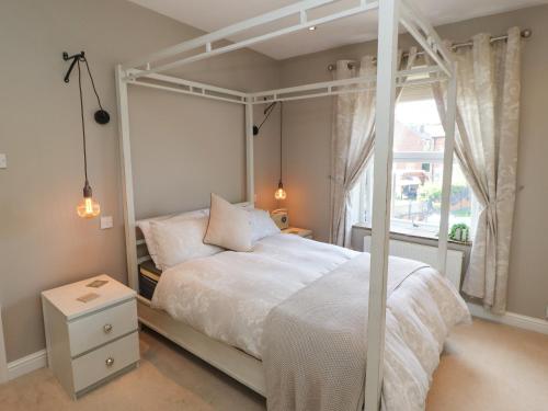 1 dormitorio con cama blanca con dosel y ventana en Olive Tree Cottage, en Holmfirth