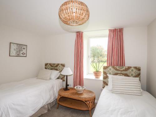 a bedroom with two beds and a window and a table at Bryn Odol Bach in Pwllheli
