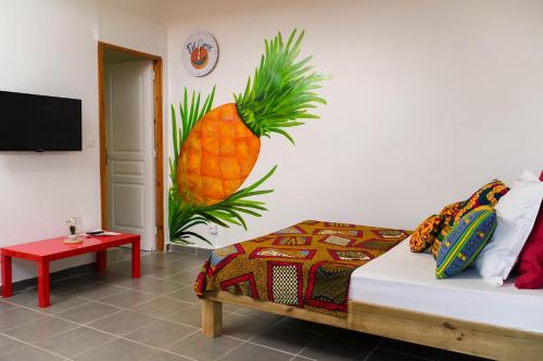 Zimmer mit einem Bett mit Ananas an der Wand in der Unterkunft Bel'oasis in Le Lamentin