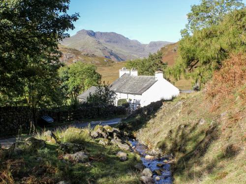 a cottage on the side of a hill with a stream at Windermere in Kendal