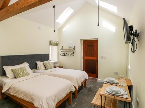 two beds in a room with a table and a tv at Nythfa - 3 Plough & Harrow in Cowbridge