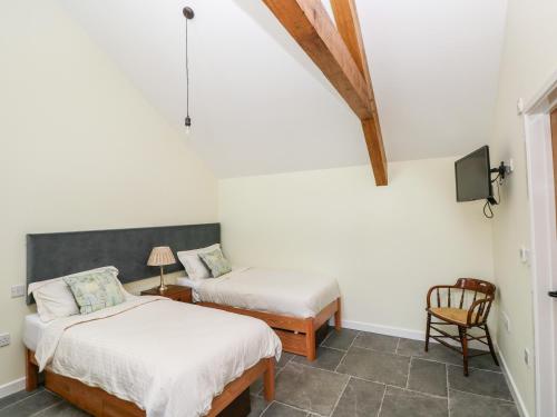 a bedroom with two beds and a chair at Trefechan - 4 Plough & Harrow in Cowbridge