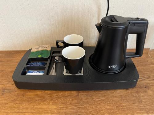 a black coffee maker and two cups on a tray at Hotel Radetzky in Sankt Gilgen