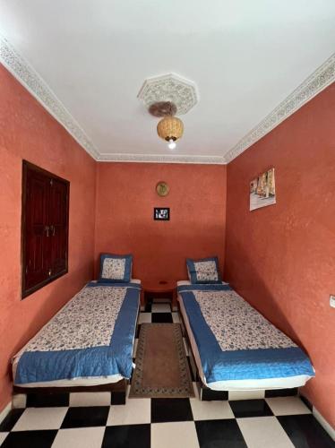 2 camas en una habitación con paredes rojas en Riad Elijah Marrakech & Spa, en Marrakech