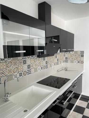 - une cuisine avec du carrelage noir et blanc sur le mur dans l'établissement Gîte-appart privé du Domaine Spa piscine sauna, à Lescout