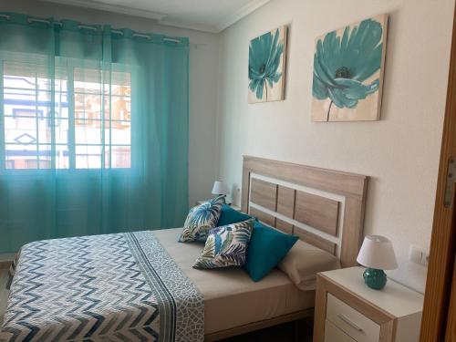 a bedroom with a bed with blue curtains and a window at Adosado playa, geoda y Aguilas cerca, con barbacoa y piscina en San Juan de los terreros in San Juan de los Terreros