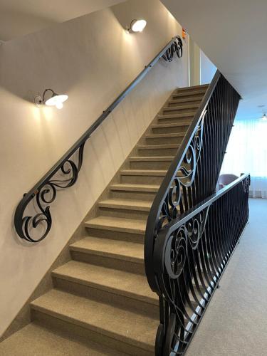 a staircase with a black metal railing and a stair case at Hotel Radetzky in Sankt Gilgen