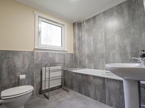 a bathroom with a toilet and a sink and a tub at Garden Lodge in Muir of Ord