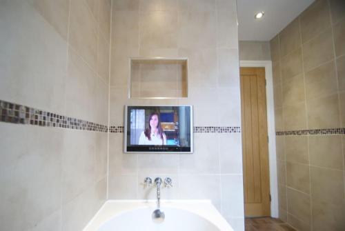 a bathroom with a sink and a tv on the wall at Cosy Family Home Near the Quay in Exeter