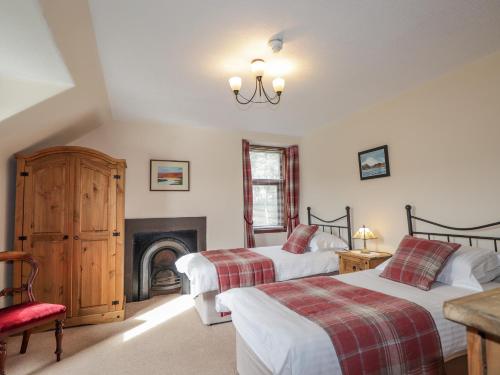 1 dormitorio con 2 camas y chimenea en Balloan House, en Muir of Ord