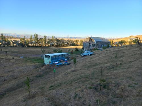 a bus parked in a field next to a house at Guest House AREVIK in Artsvakar