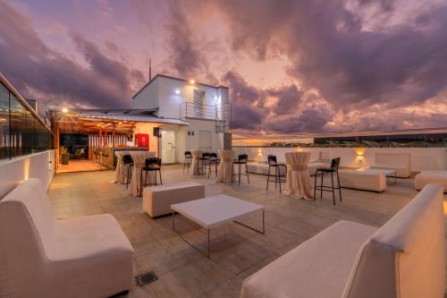 un patio en la azotea con muebles blancos y un cielo nublado en Hotel Portal del Río, en Barranquilla