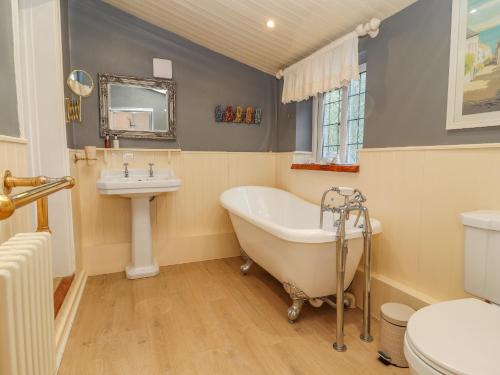 a bathroom with a tub and a sink and a toilet at Llidiart Cerrig in Dyserth
