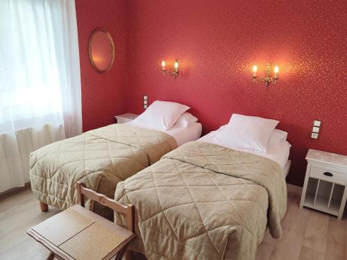 two beds in a hotel room with red walls at l'Auberge des Gourmets Hôtel Restaurant in Le Vaudioux