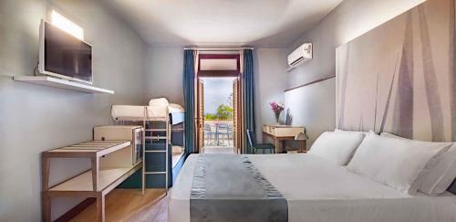 a bedroom with a bed and a desk and a window at Hotel Baia Imperiale in Campo nell'Elba