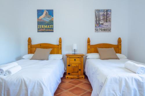 a room with two beds and a nightstand between them at Cubo's Finca Los Acebuches in Alhaurín el Grande