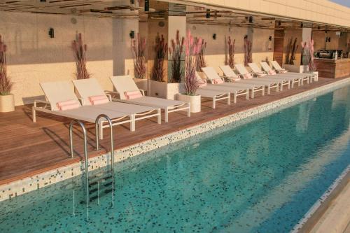 una piscina con tumbonas y una piscina en The House Hotel Al Khiran en Al Khīrān