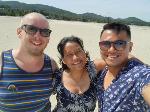 three people posing for a picture on the beach at BeauBo Beach in Baan Tai