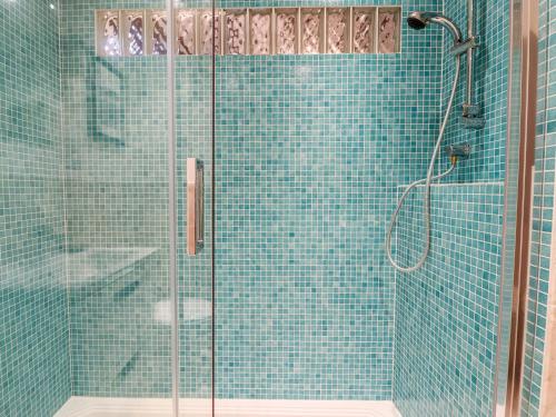 a bathroom with a shower with blue tiles at The Hayloft in Kingsbridge