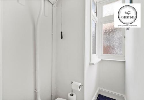 een witte badkamer met een toilet en een raam bij 3 Bedroom House with Parking & Garden By Cherry Inn Short Lets & Serviced Accommodation Cambridge in Cambridge