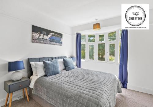 a bedroom with a bed with blue curtains and a window at 3 Bedroom House with Parking & Garden By Cherry Inn Short Lets & Serviced Accommodation Cambridge in Cambridge