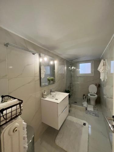 a white bathroom with a sink and a toilet at Modern apartment in the heart of Athens. in Athens