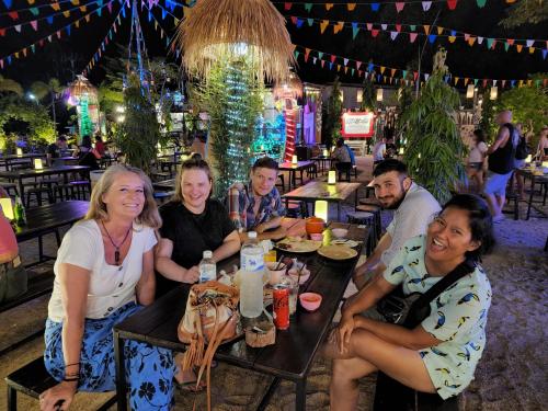 een groep mensen aan een tafel in een restaurant bij BeauBo Beach in Baan Tai